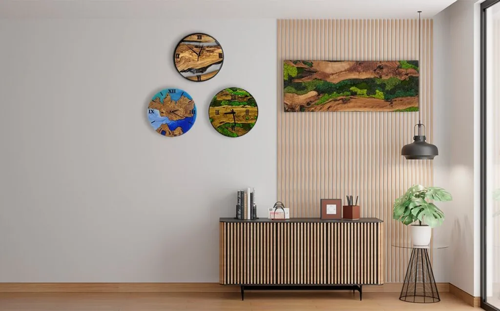 A collection of artisan wall decor featuring a round epoxy clock, an olive wood clock, and olive wood with moss wall art.