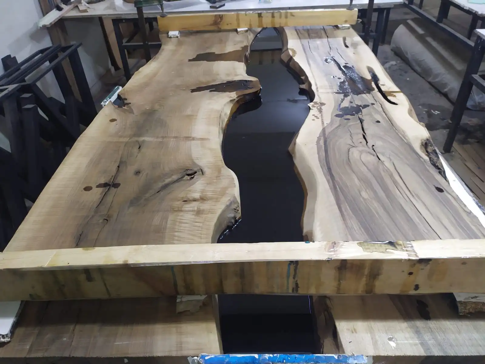 The seamless transition between the natural live edge walnut wood and the black resin on a live edge epoxy table.